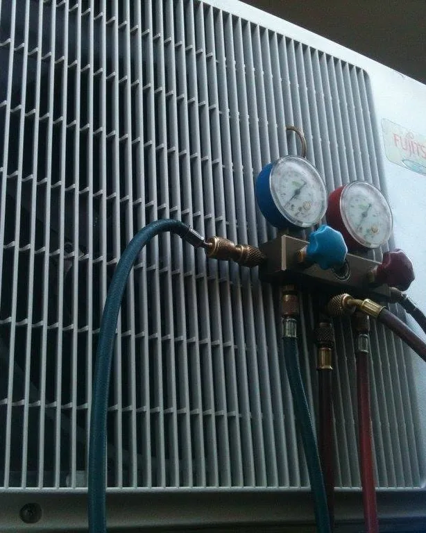 Michael's refrigerant gauges connected to a Fujitsu split system outdoor unit during an air con service