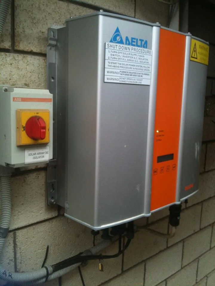 A grid-connect solar inverter with its rooftop isolator mounted on a brick wall